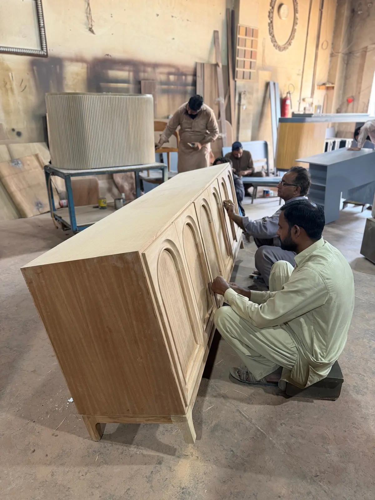 Craftsmen finishing an arched sideboard in raw oak